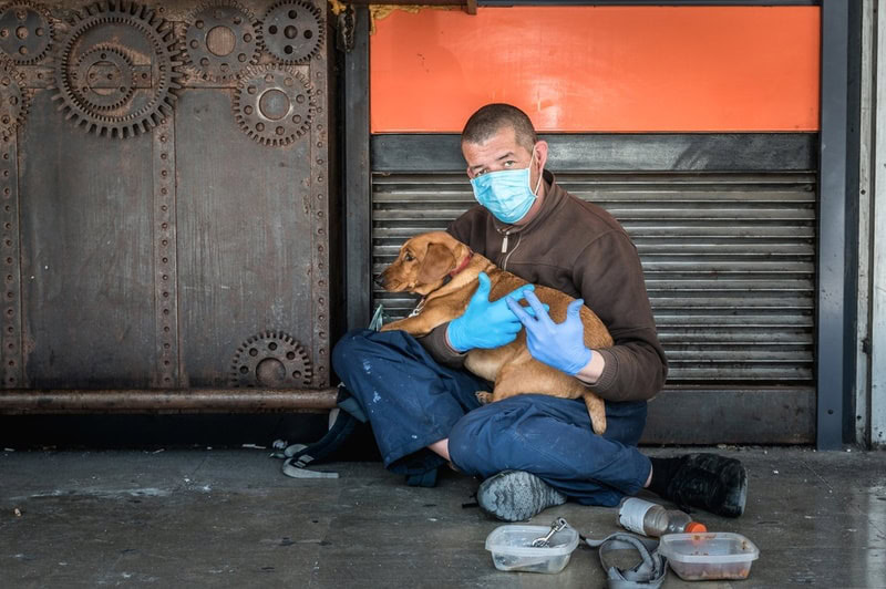 A homeless man with pet dog on his lap