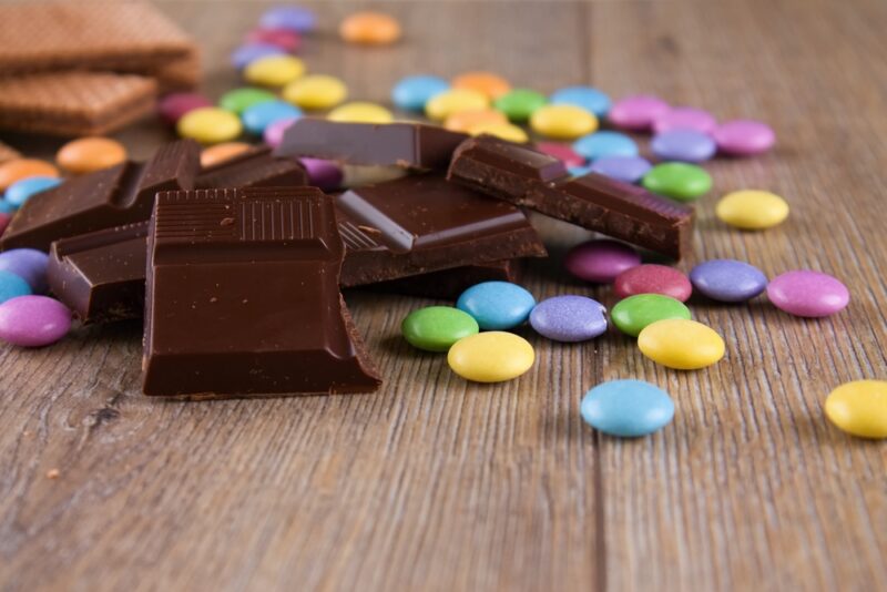 Horizontal photo with heap of dark chocolate pieces on wooden board