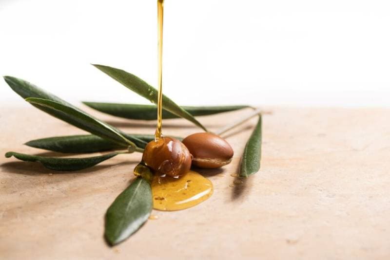 argan oil pouring over two argan seeds
