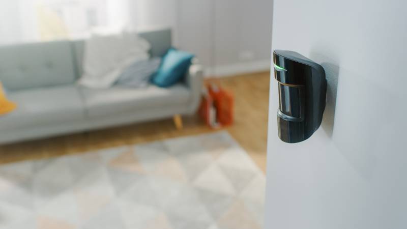 modern movement detector unit on a white wall in a cozy apartment in the background
