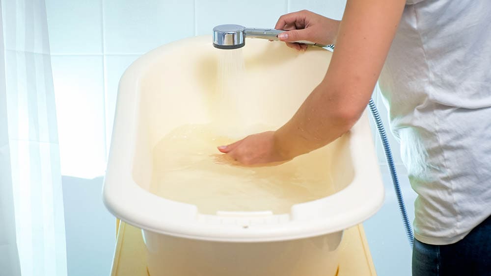 person filling up tub with water