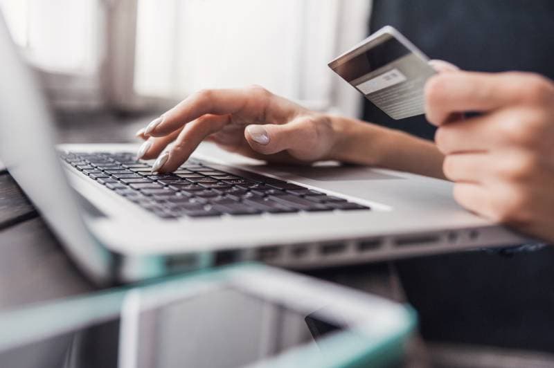 woman holding credit card and using laptop doing online shopping