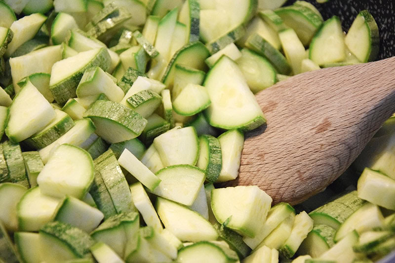 wooden spoon on sliced zucchinis